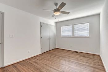 an empty living room with a ceiling fan and a closet
