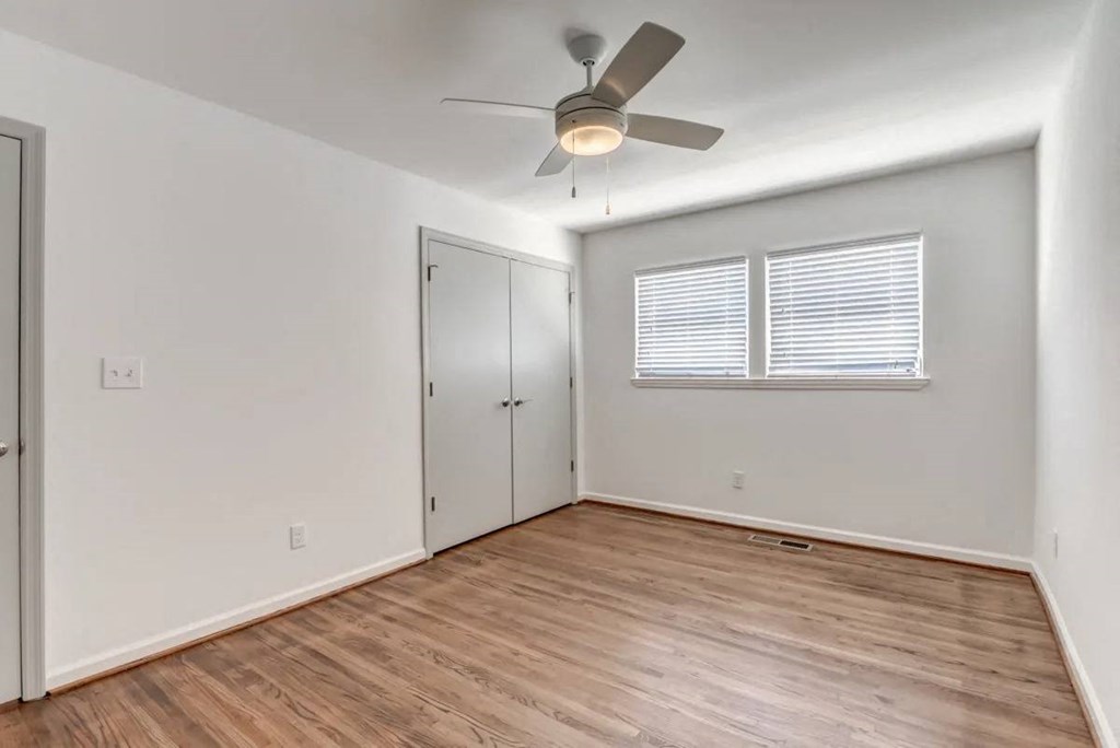 an empty living room with a ceiling fan and a closet