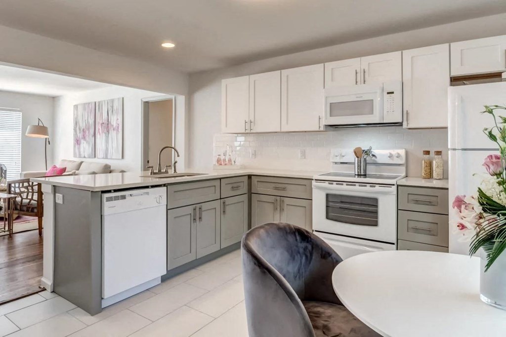 a white kitchen with white appliances and a table