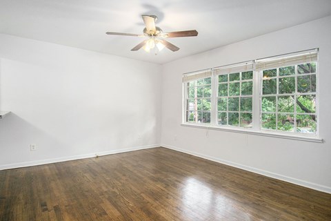 A room with a ceiling fan and a window with a view of trees.
