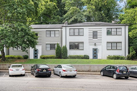 A grey building with a black door and a green lawn in front.