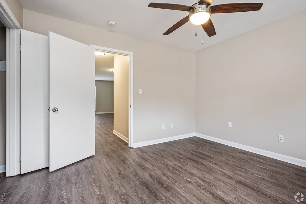 A room with a ceiling fan and light, and a door with a white frame.