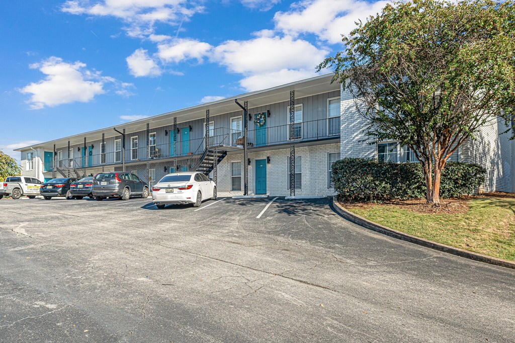 A white car is parked in a parking lot in front of a building.