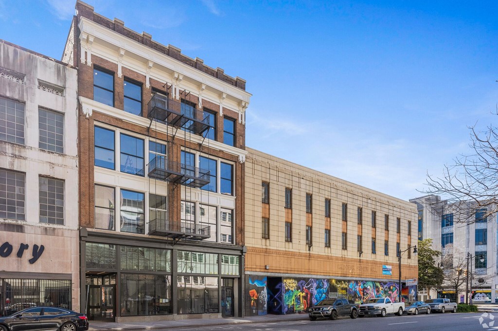 A street view of a building with a mural on the side.