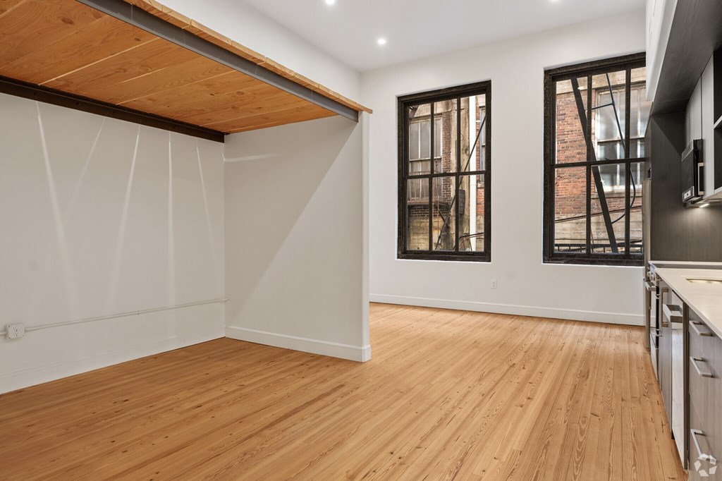 A room with wooden floors and a window with bars on it.