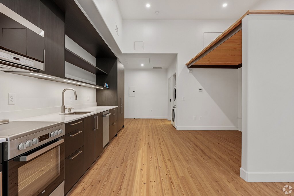 A modern kitchen with wooden floors and stainless steel appliances.