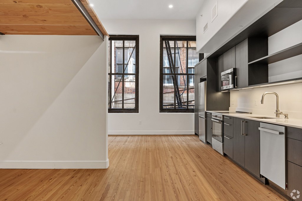 A kitchen with wooden floors and a white wall.