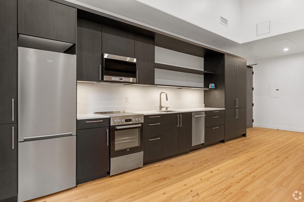 A modern kitchen with dark wood cabinets and stainless steel appliances.