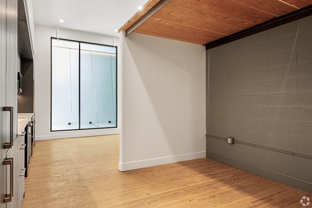 A room with a wooden floor and a wall with a grey brick pattern.