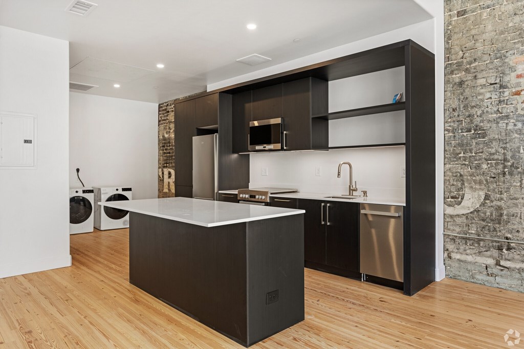 A modern kitchen with a large island and dark wood cabinets.