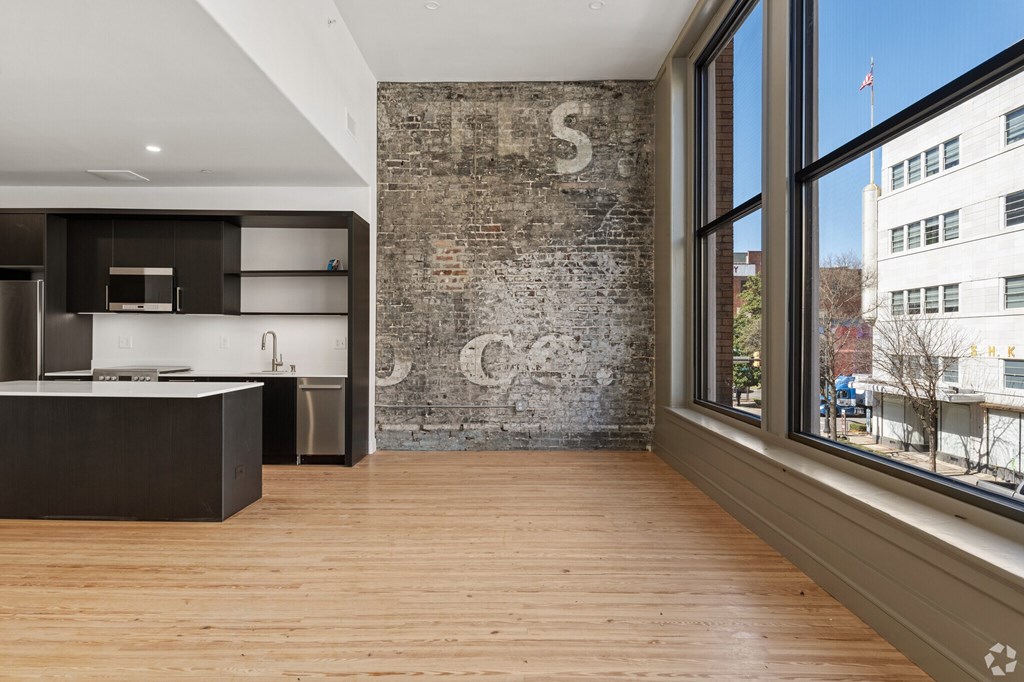 A kitchen with a wooden floor and a brick wall with a letter S on it.