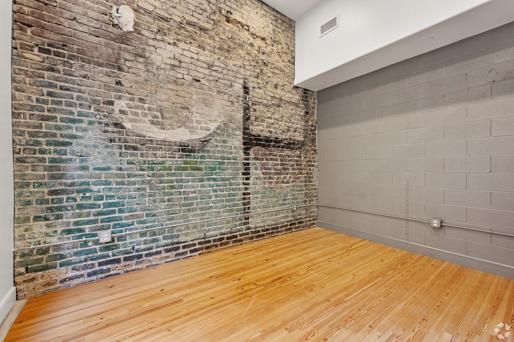 A room with a brick wall and wooden floor.