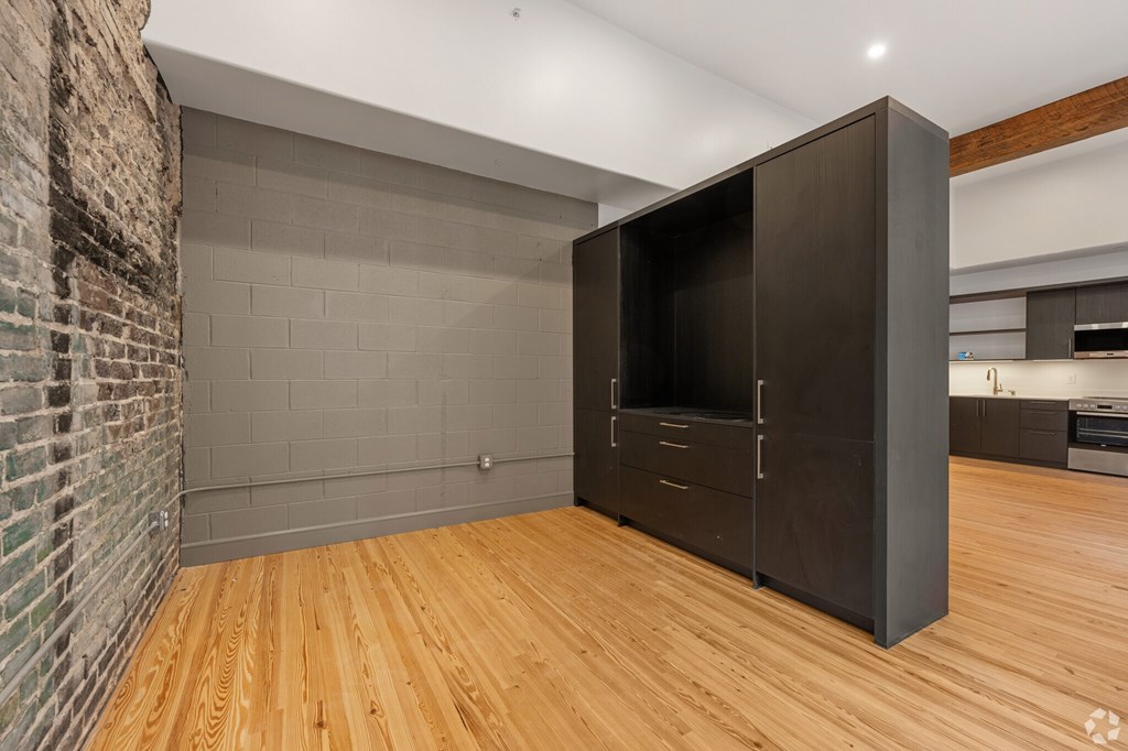 A room with a wooden floor and a large black wardrobe.