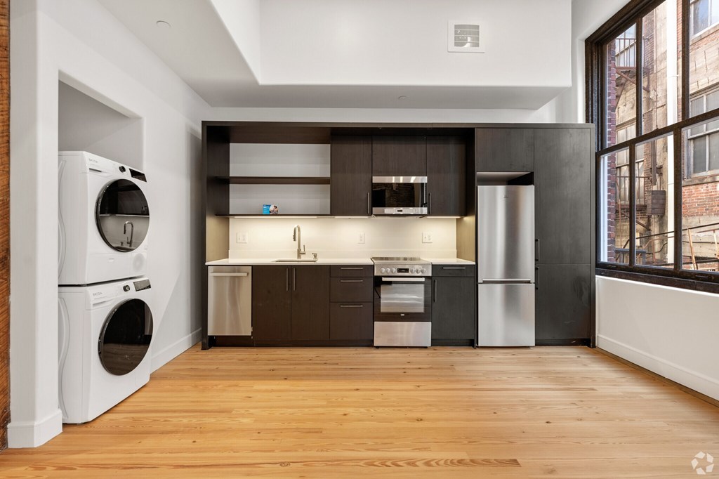 A modern kitchen with wooden floors and stainless steel appliances.