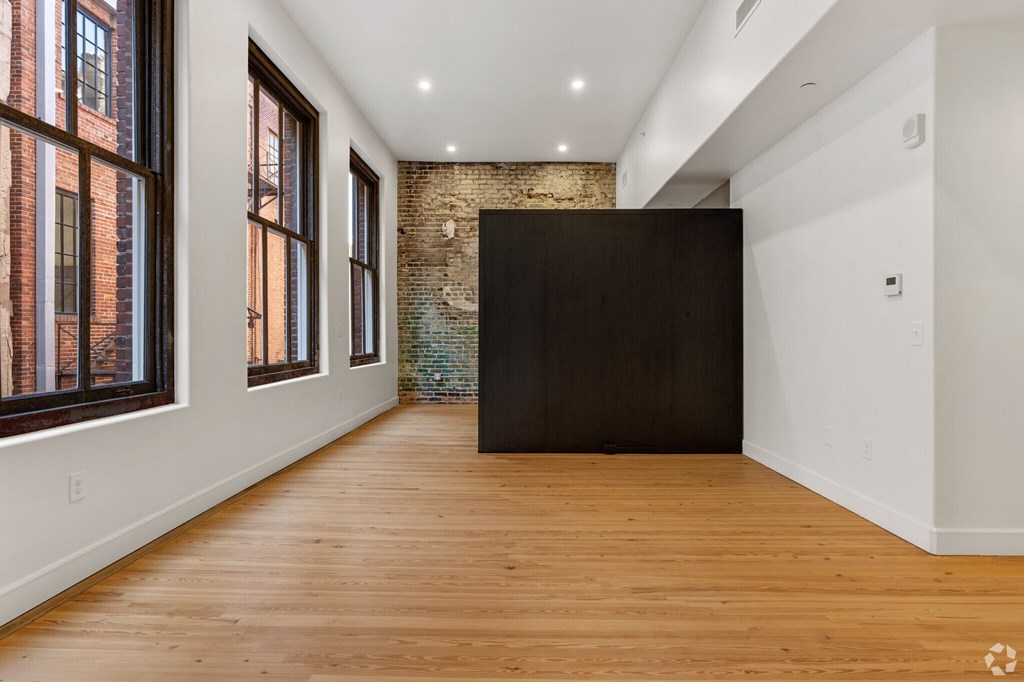 A room with wooden floors and a brick wall.