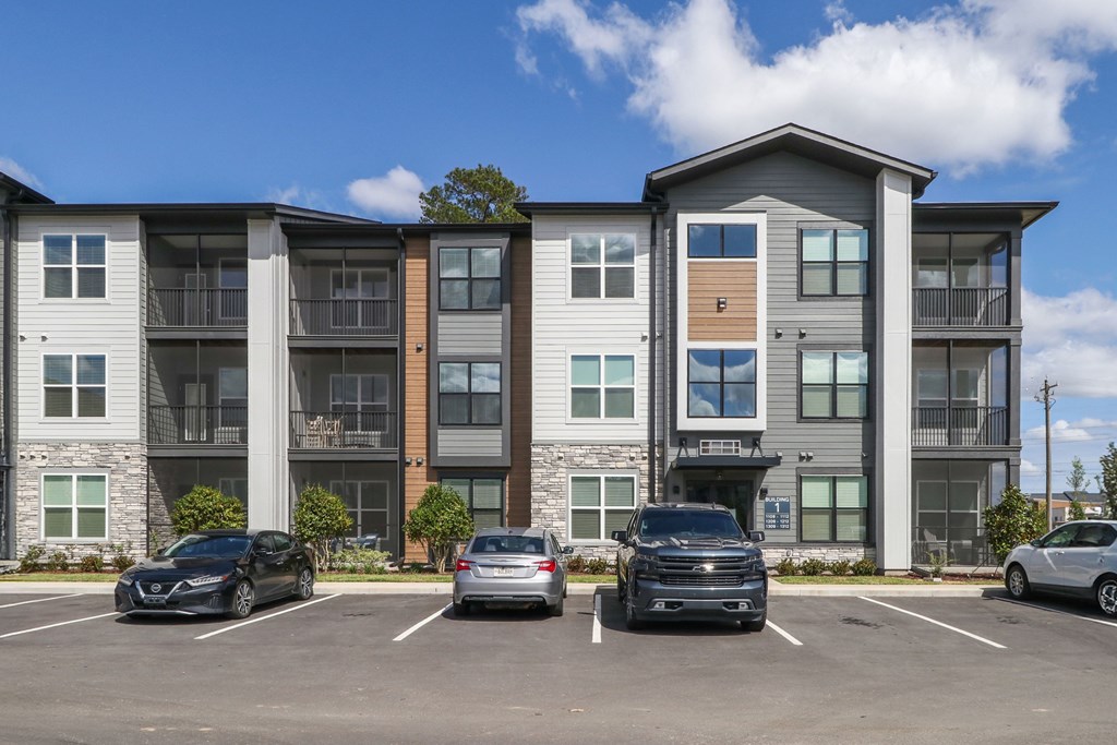 A row of townhouses with cars parked in front.