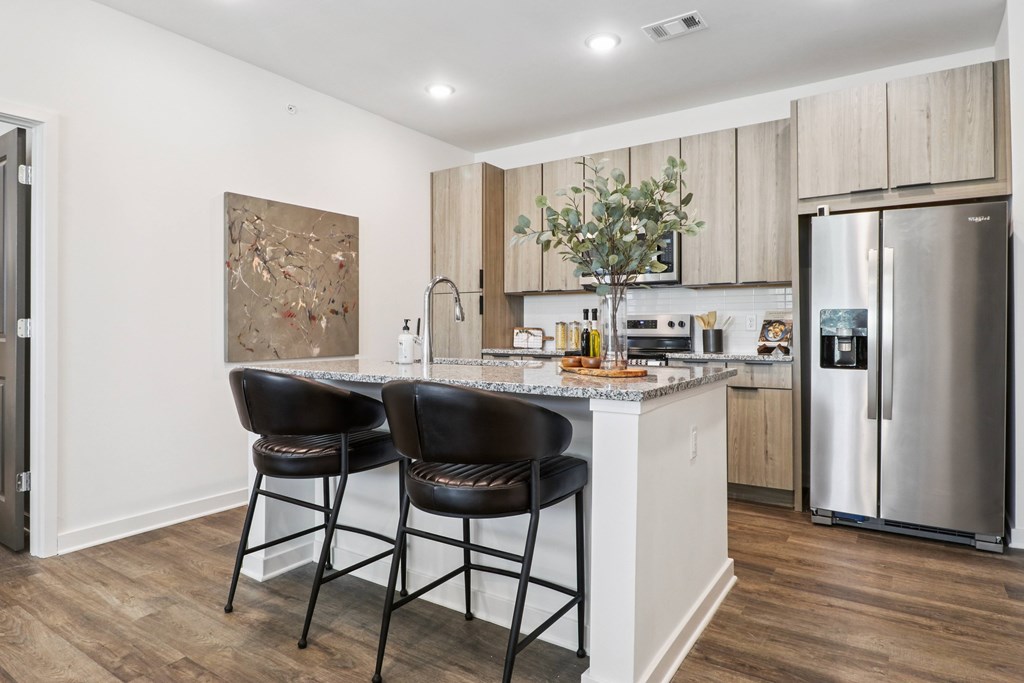 A kitchen with a marble countertop and a painting on the wall.