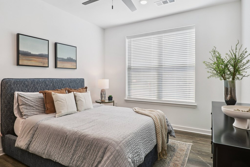 A bedroom with a bed, a nightstand, and a plant.