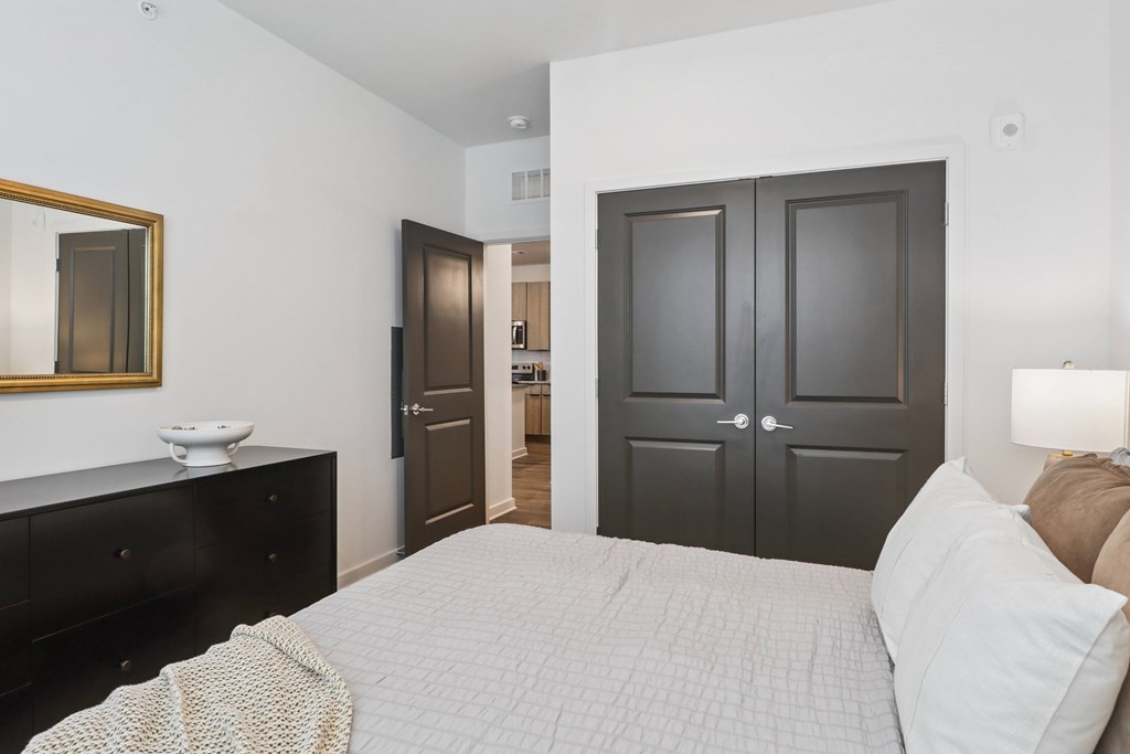 A bedroom with a bed, dresser, and mirror.