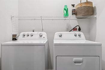 Two white front loading washing machines in a laundry room.