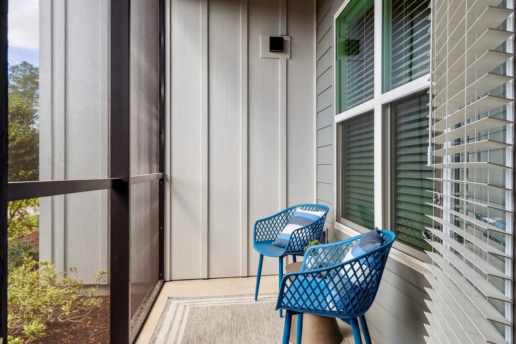 Two blue chairs are on a porch.