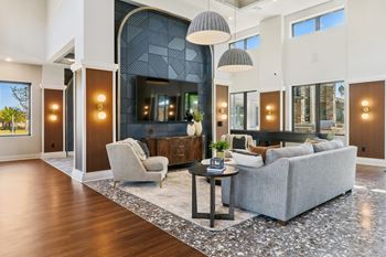 A modern living room with a grey sofa, a white armchair, and a patterned rug.