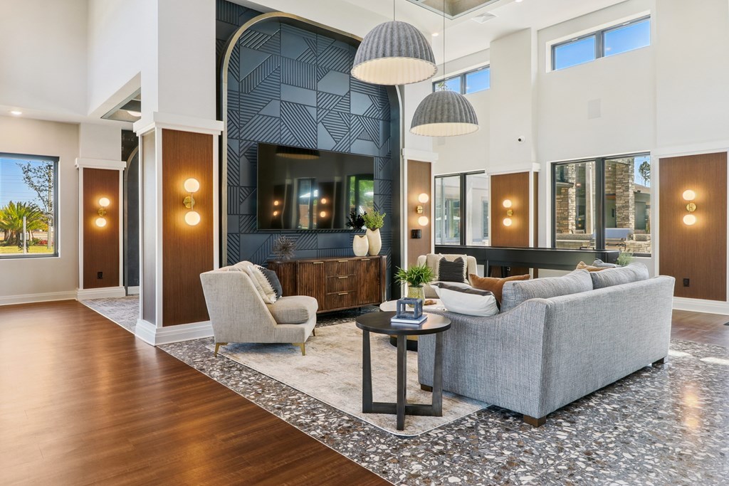 A modern living room with a grey sofa, a white armchair, and a patterned rug.