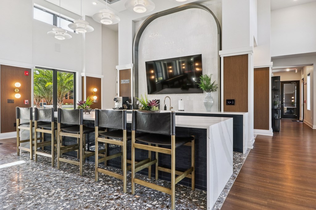 A long table with chairs is in the middle of a room with a TV on the wall.