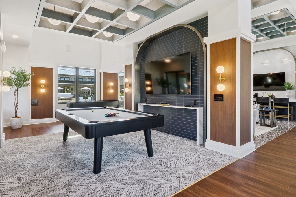 A pool table is in the middle of a room with a brick wall and a mirror.