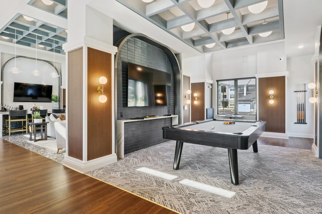 A billiard table is in the middle of a room with a TV and a couch.