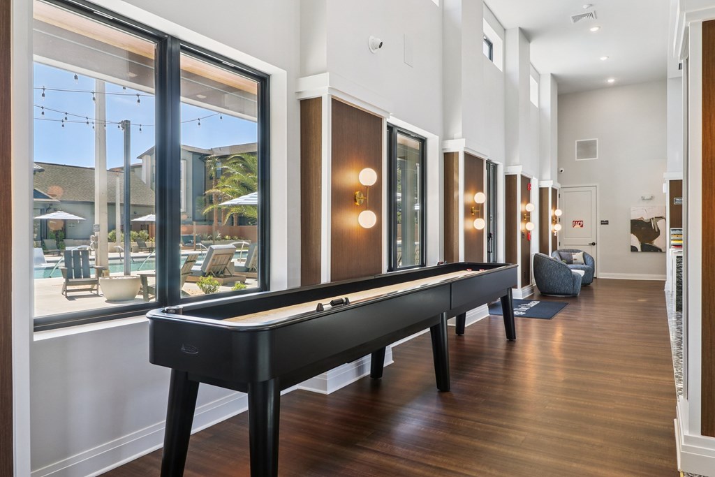A pool table is in the middle of a room with a view of the outside.