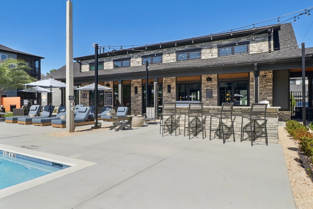 A poolside area with lounge chairs and a building in the background.