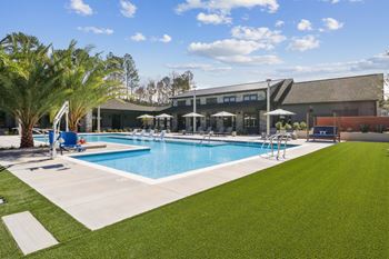A large swimming pool with lounge chairs and a building in the background.
