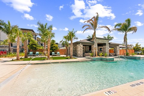 A swimming pool surrounded by palm trees and a house in the background.