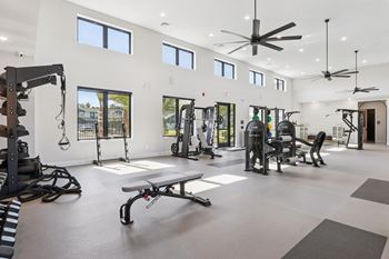 A spacious gym with a variety of equipment and a large mirror on the wall.