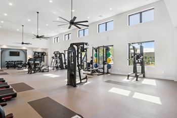 A spacious gym with a variety of equipment and a ceiling fan.