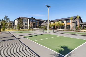 A tennis court is in the foreground with a building in the background.