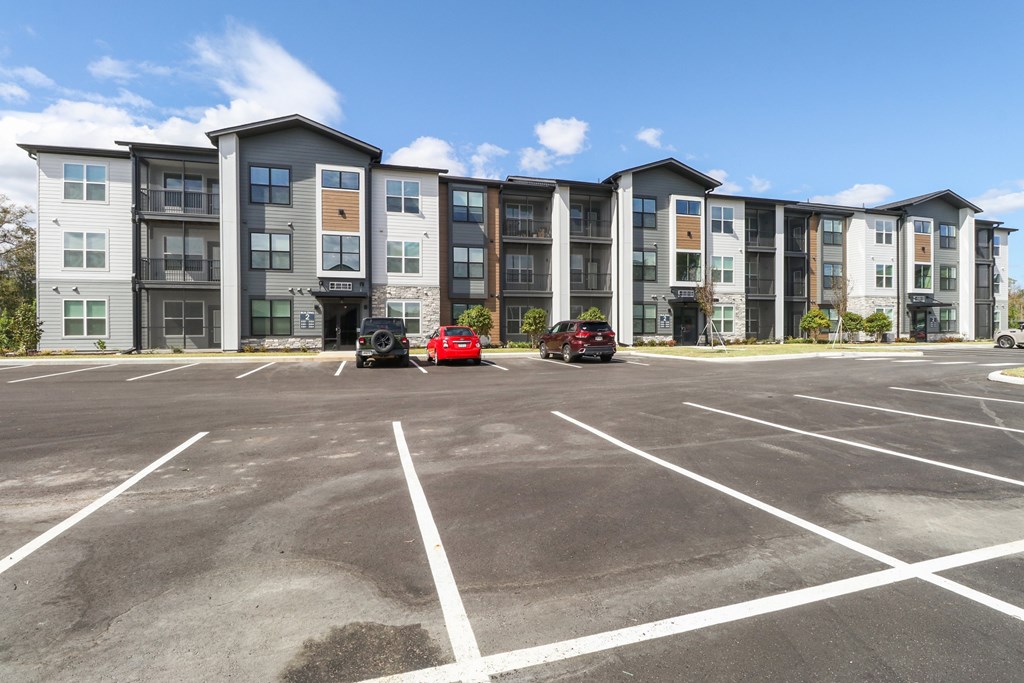 A parking lot in front of a multi-story apartment building.