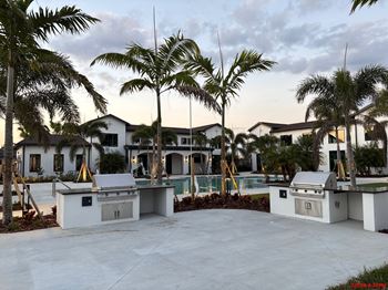 A white outdoor kitchen area with palm trees in the background.