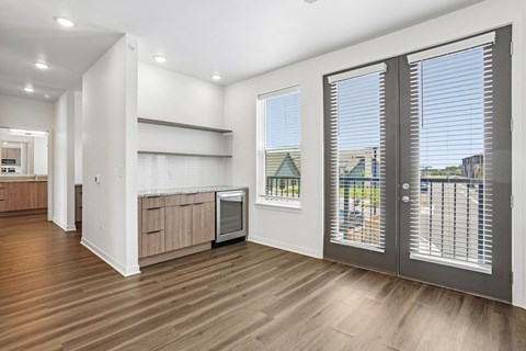 A kitchen with a wooden floor and a window with blinds.