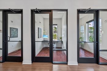 Three black doors open to a hallway with a red floor at The Hadley - North Port, FL Apartments, Florida
