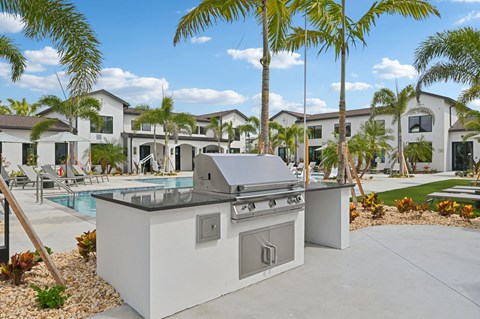 A modern outdoor kitchen with a grill and sink is set up in front of a row of houses.
