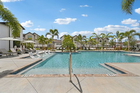 A pool surrounded by palm trees and lounge chairs. at The Hadley - North Port, FL Apartments, North Port 34287