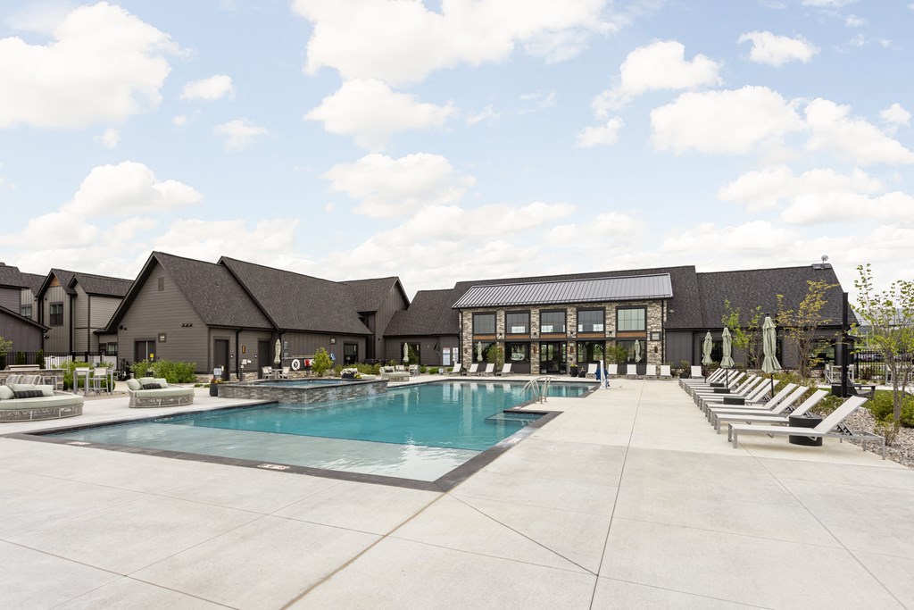 a swimming pool with lounge chairs in front of a building