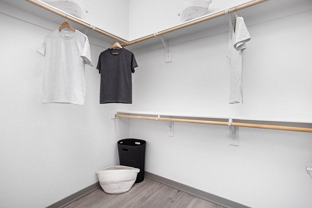 a large white closet with two shirts and a trash can
