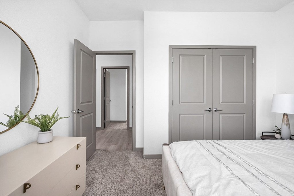 a bedroom with white walls and a bed and a dresser with a mirror