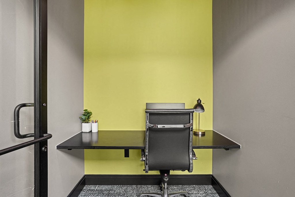 a desk with a chair in a room with a yellow wall