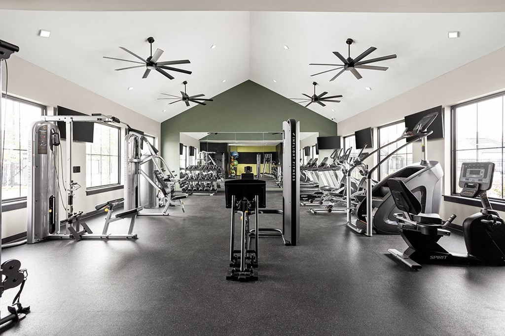 a gym with weights and cardio equipment on the floor and windows
