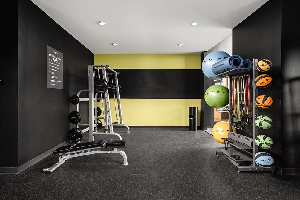 a gym with weights and other equipment in a room with a yellow and black wall