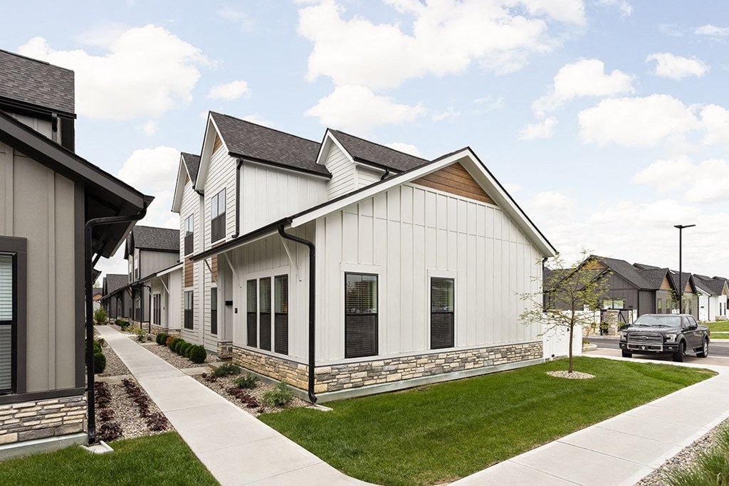 a row of white houses with a sidewalk and grass